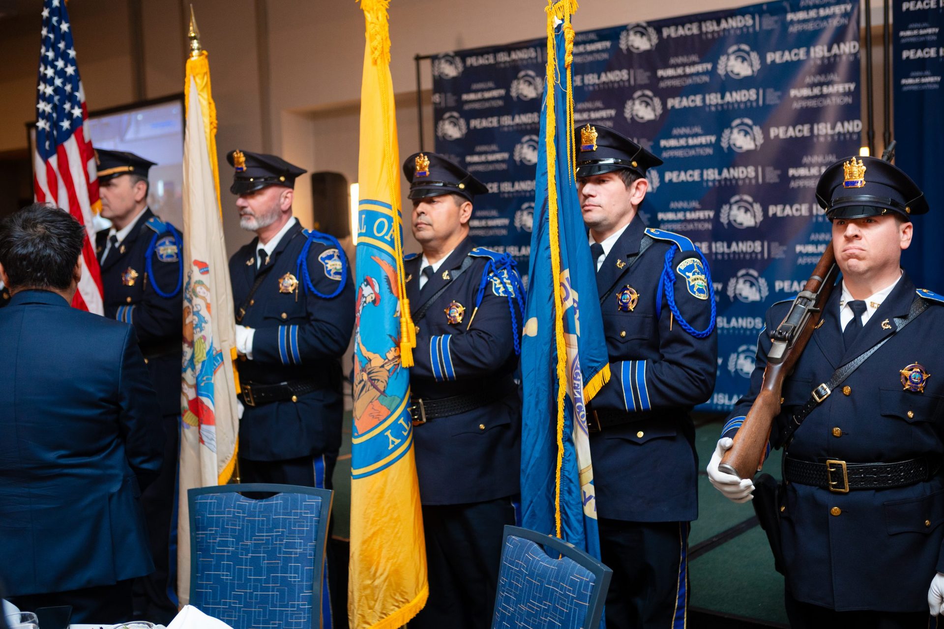 Uniformed honor guard members stand with flags at a Public Safety Appreciation dinner